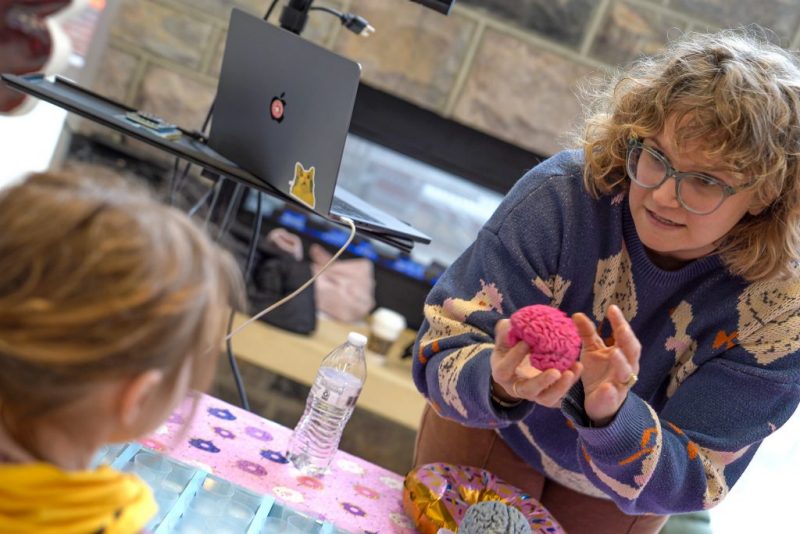 A Virginia Tech HNFE faculty member shows a small child a 3D printed model of a brain during a presentation.